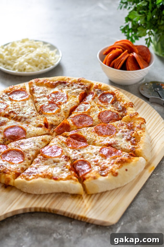 A homemade pizza sitting on a wooden pizza peel at an angle showing off the melted cheese.