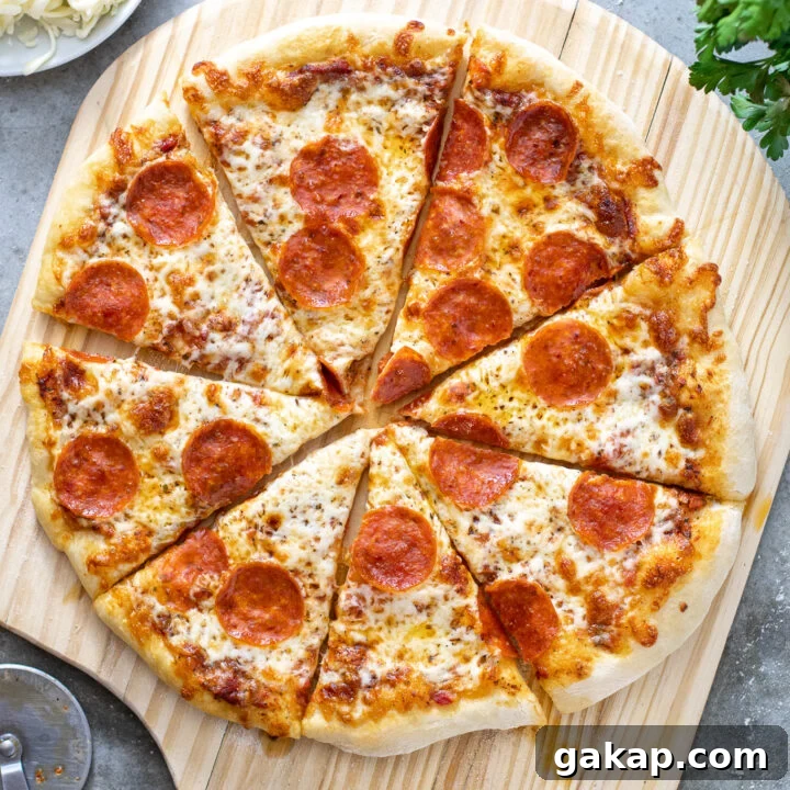 A cooked and cut pizza showing of how to make home pizza on a wooden pizza peel surrounded by ingredients.