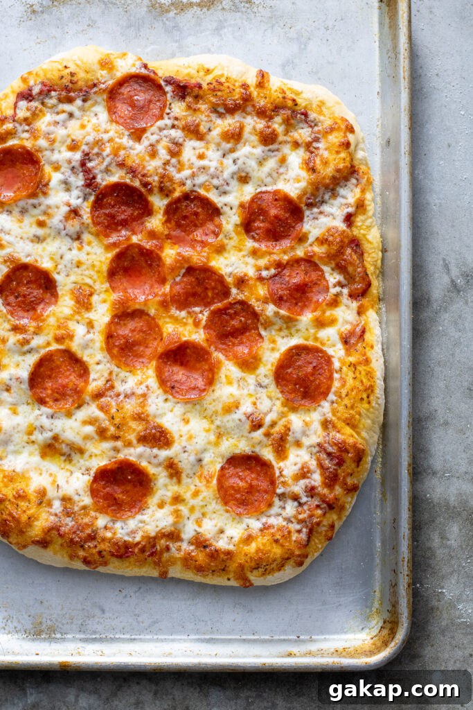Cooked pizza with melted cheese and pepperoni on a sheet pan.