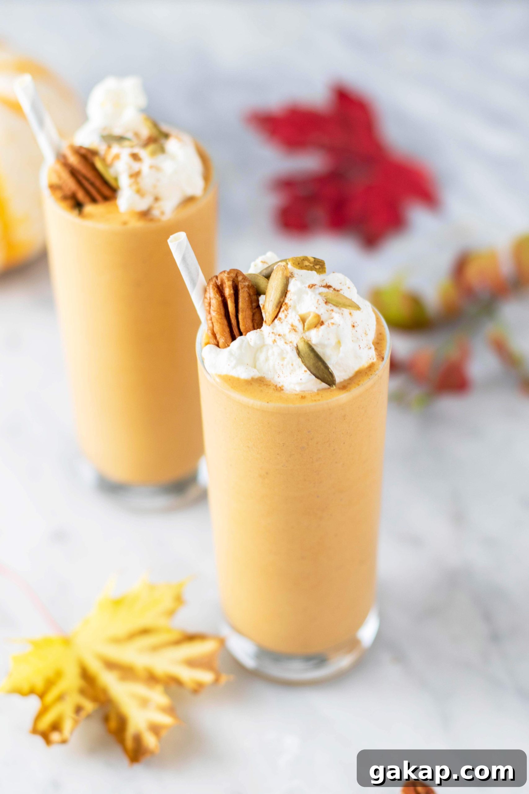 Pumpkin Spice Latte Smoothie Recipe — Fall Coffee Smoothie 2 Two pumpkin spice lattes in clear glasses, topped with whipped cream and pecans.