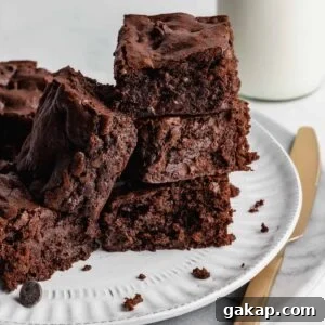 Brownies stacked on a plate with knife beside it.