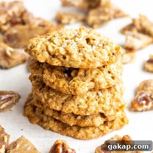 oat and pecan brittle cookies in a stack surrounded by pieces of pecan brittle