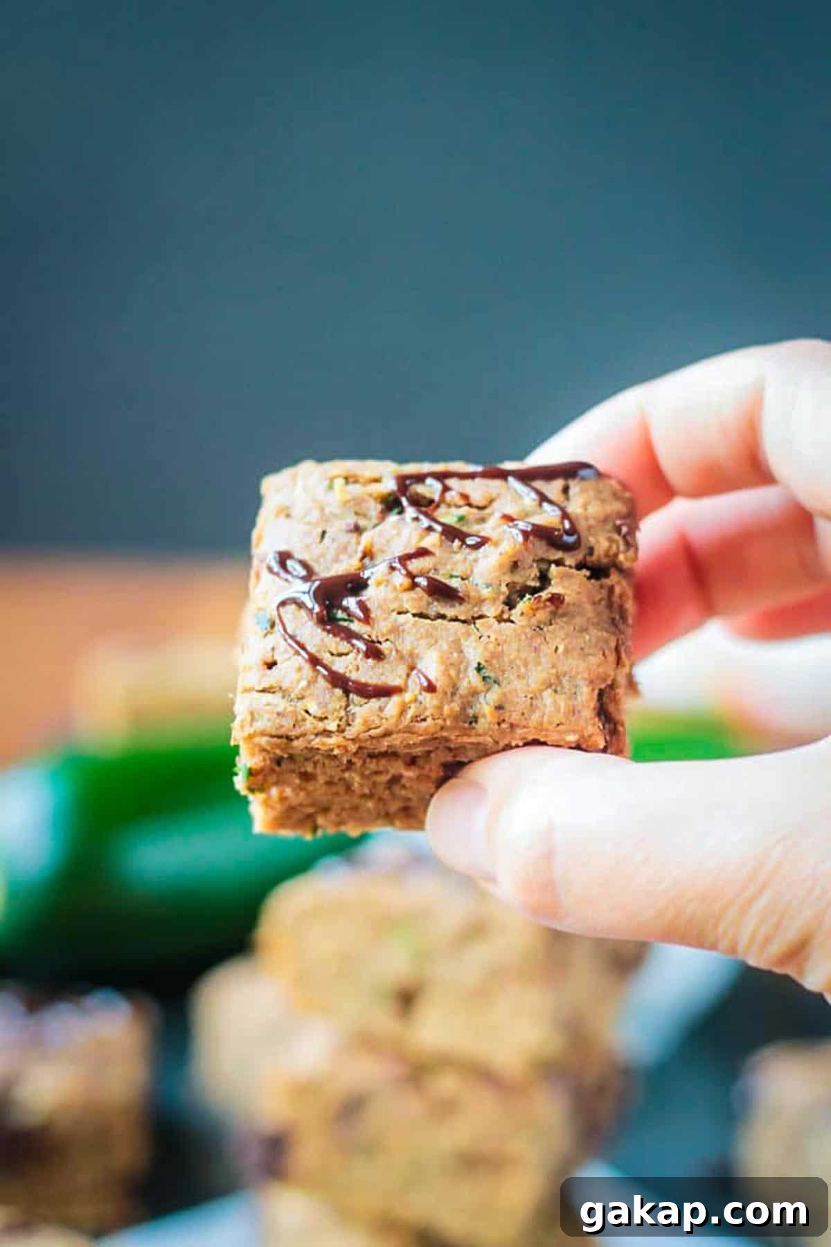Hand holding one square slice of zucchini cake.