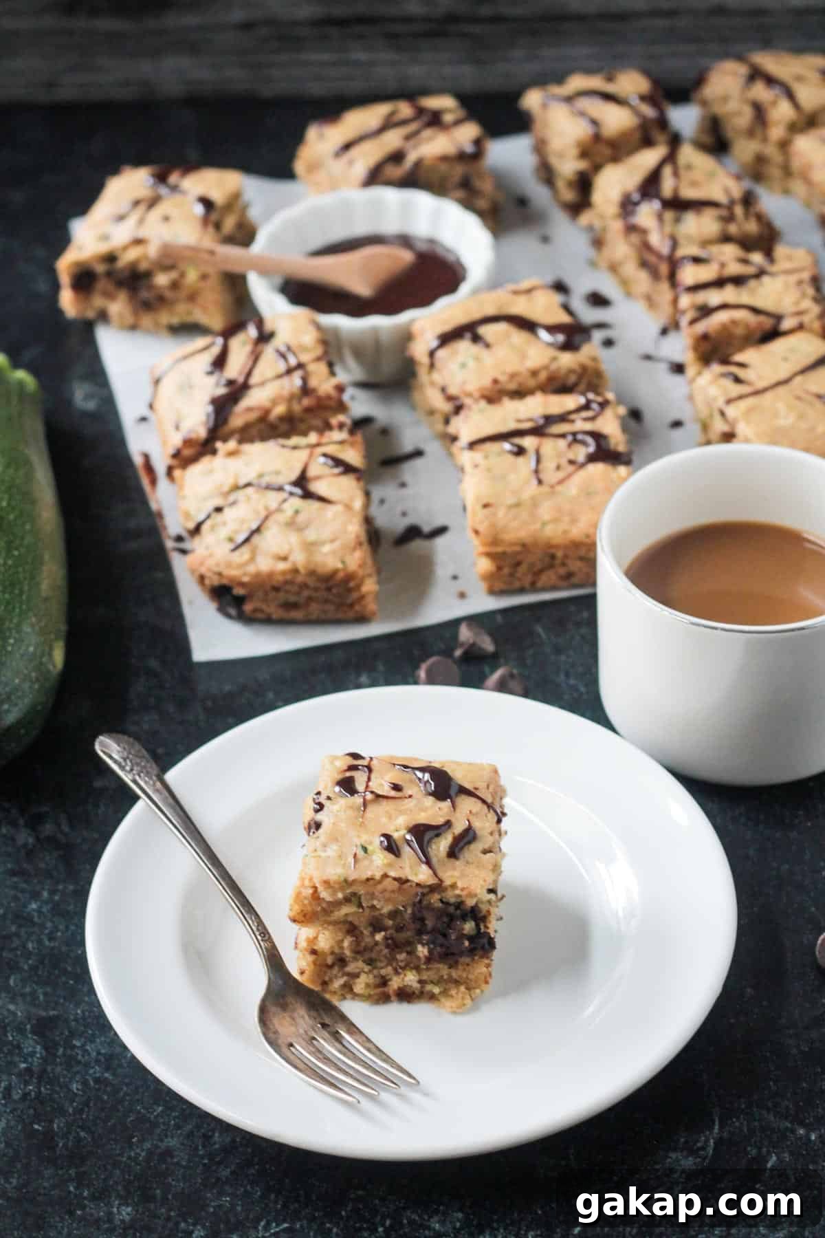 Piece of cake on a plate in front of more pieces of cake on a large piece of parchment paper.