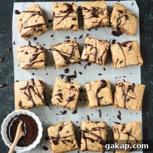 Squares of chocolate chip zucchini cake drizzled in chocolate sauce.