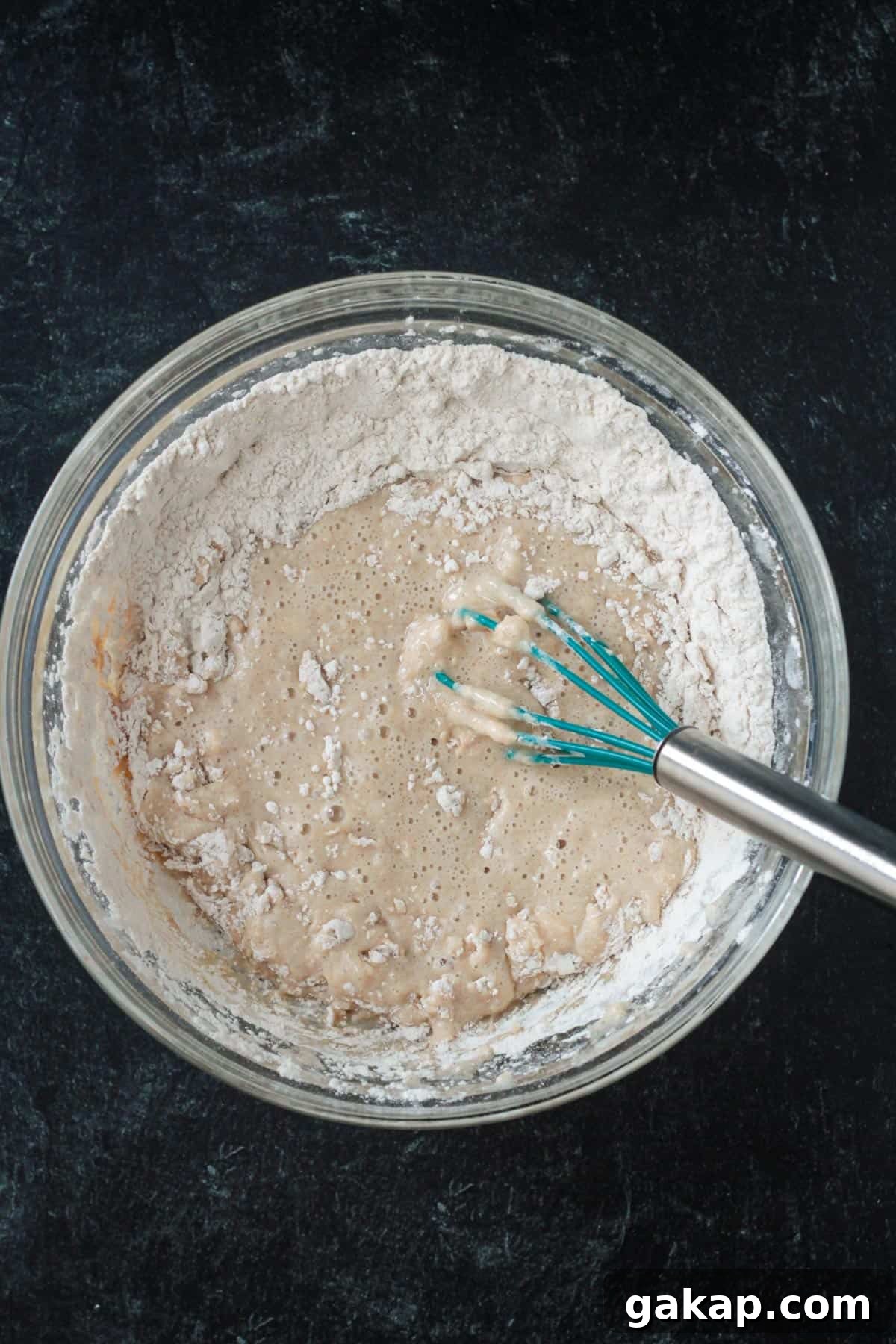Dry and wet ingredients being whisked together in a mixing bowl.