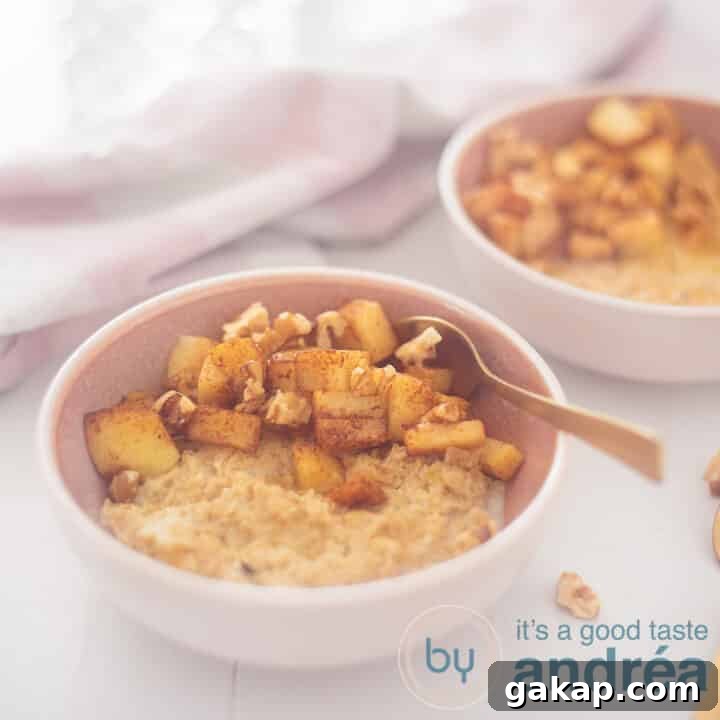 A square photo with a pink bowl in the foreground with oatmeal, apple, walnuts and honey. A golden spoon sticks into it. In the back right a second bowl. A white background with a pink and white tea towel at the top left.