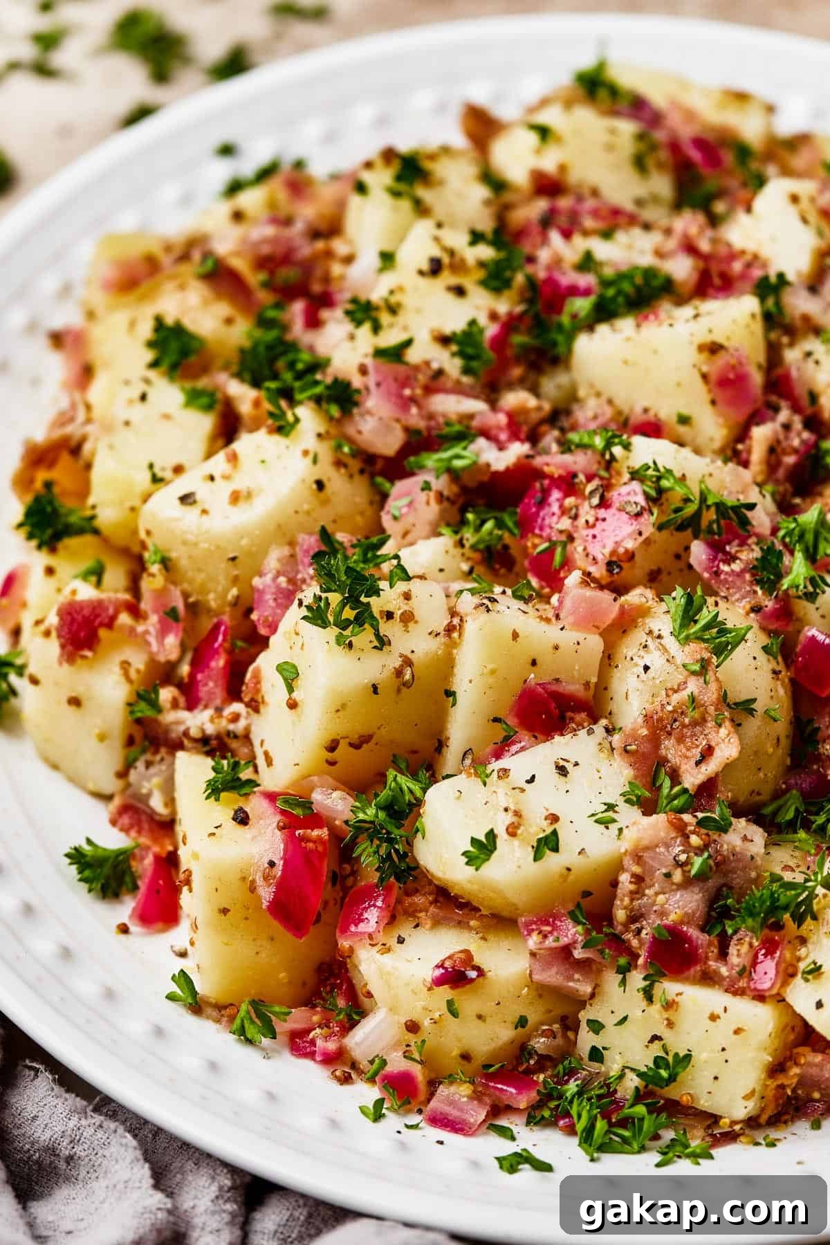 Close-up shot of chopped, boiled potatoes tossed with bacon and dressing.