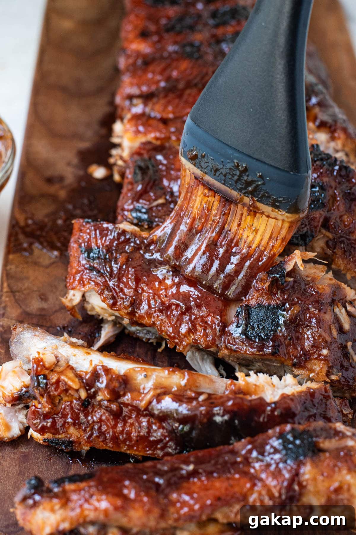 Juicy Oven-Baked BBQ Ribs Recipe for Tender, Fall-Off-the-Bone Meat 2 BBQ sauce being basted on baby back ribs