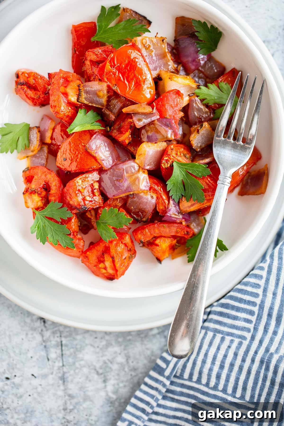 Air fried tomatoes and onions in a bowl with fresh herbs.