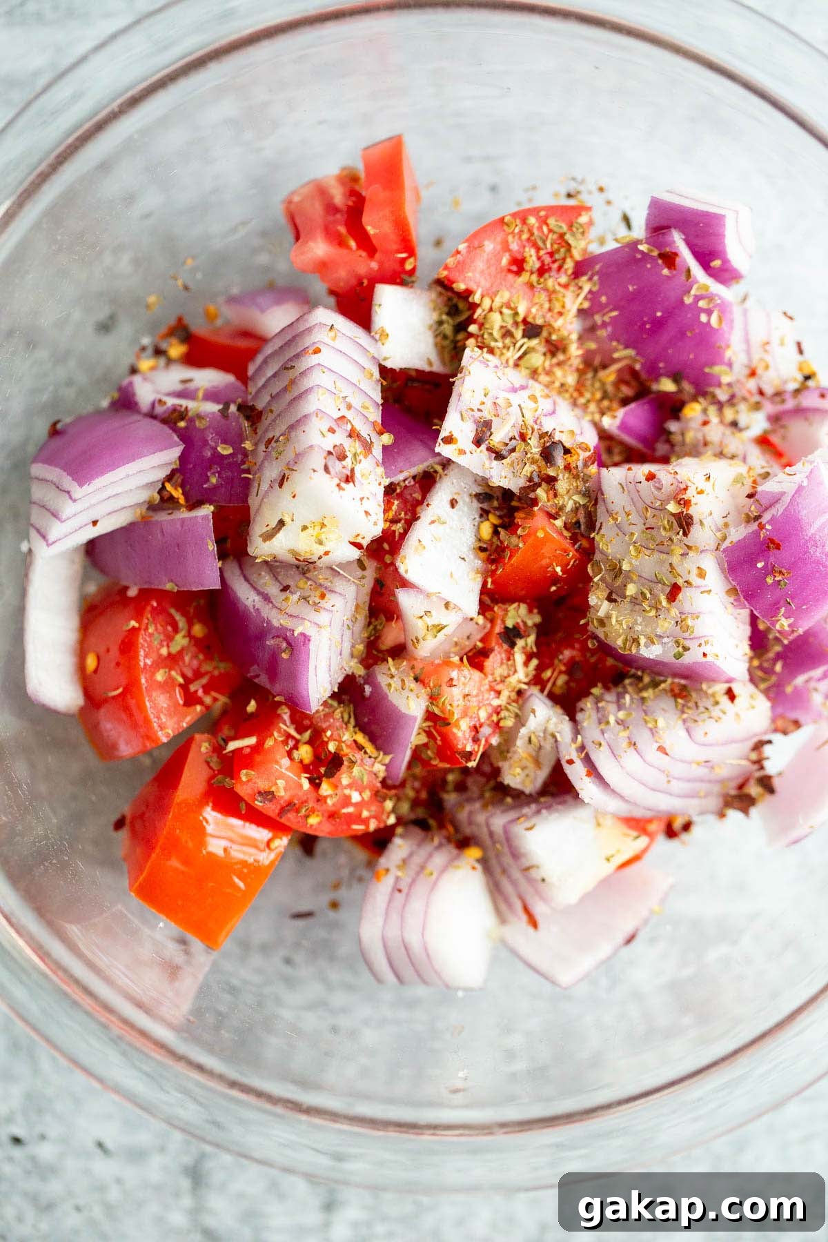 Spices and oil on tomatoes and onions.