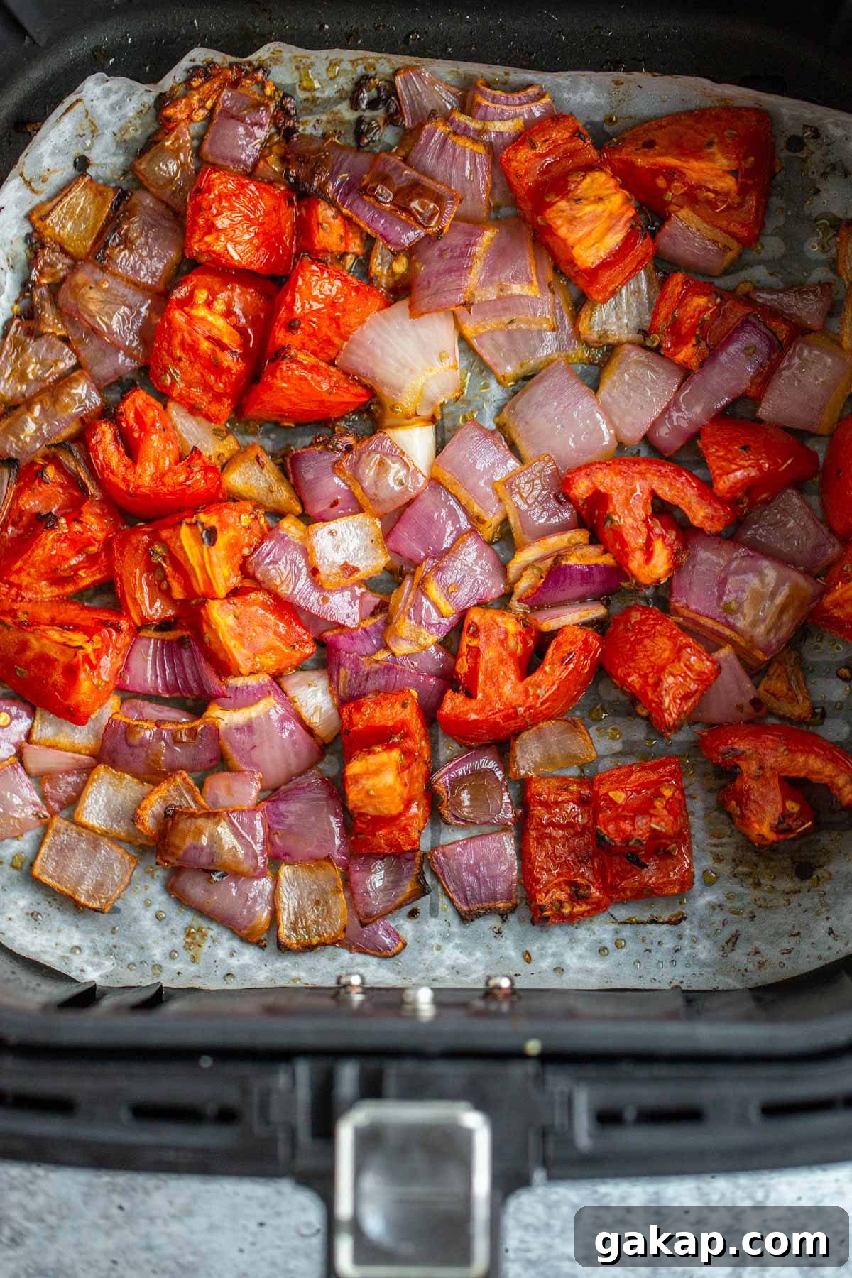 Air fried tomatoes and onions in air fryer basket.