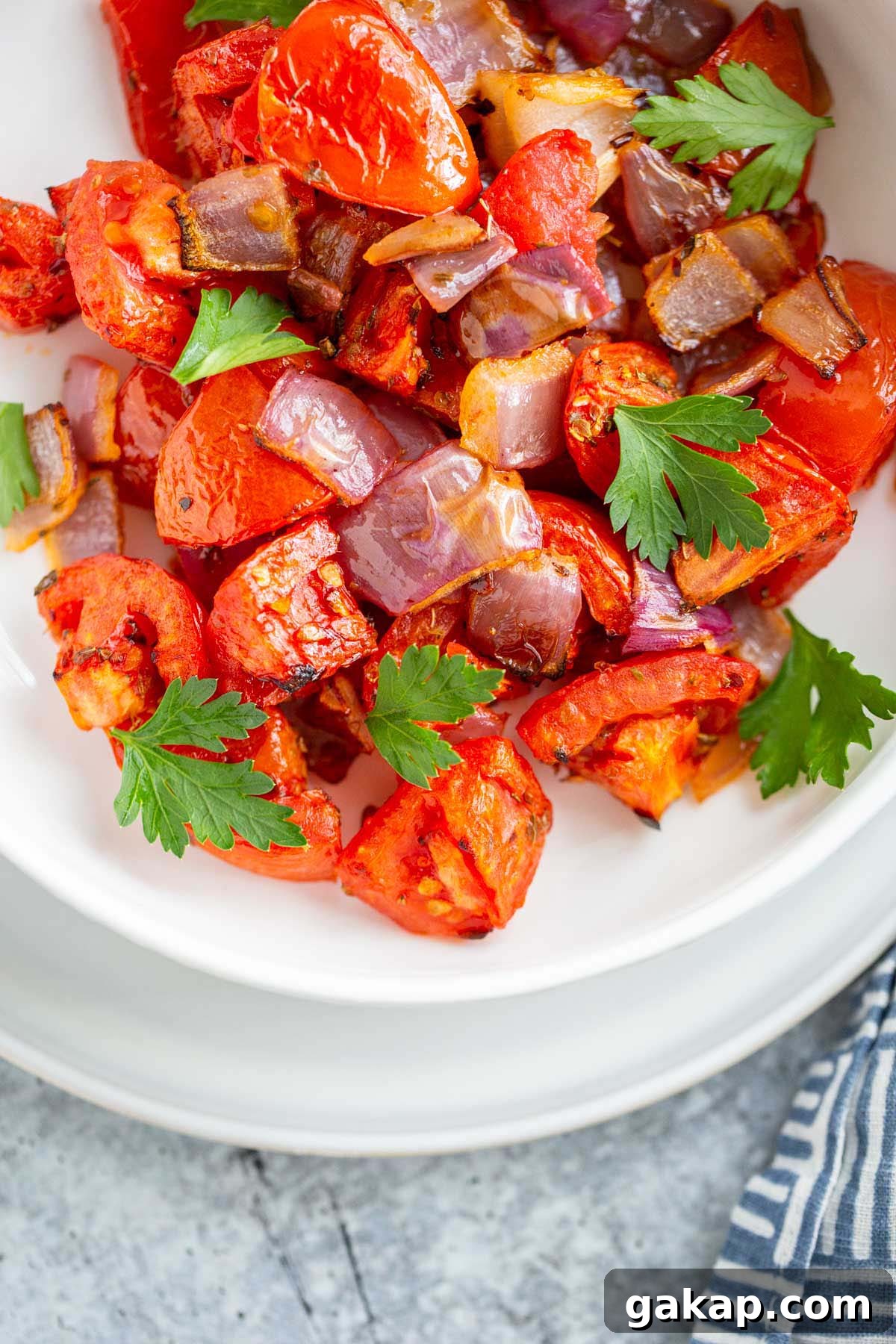 Air fried tomatoes and onions in a bowl with fresh herbs.