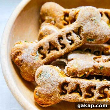 A wooden bowl with homemade dog treats and the name of the dog Sassy stamped in each of them in a pile.
