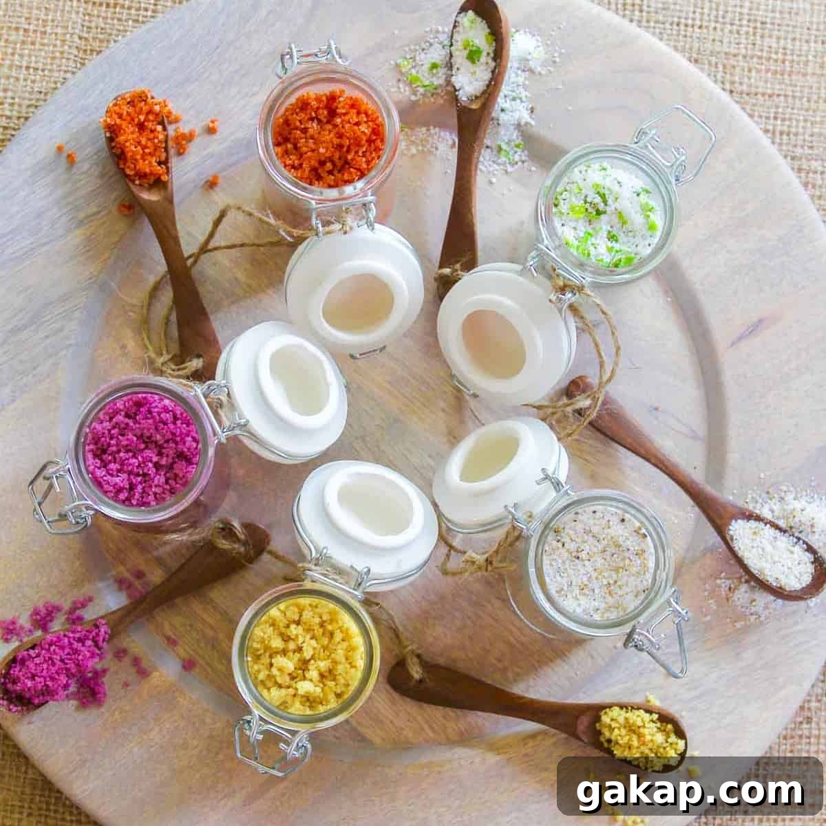 A wood platter with 5 seasoning jars open filled with flavored finishing salts.