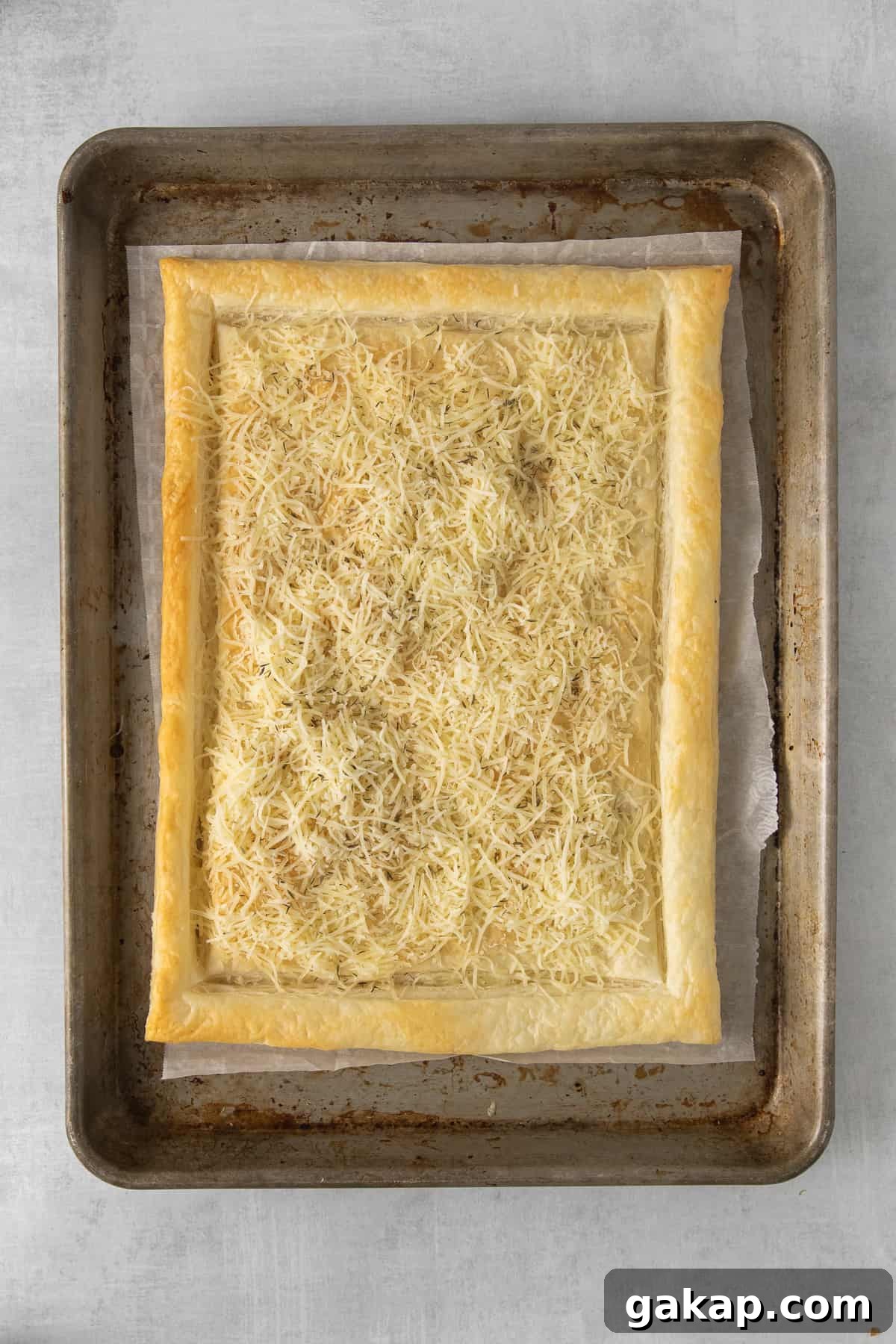 Puff pastry with cheese Puff pastry topped with shredded gruyere on a baking sheet.