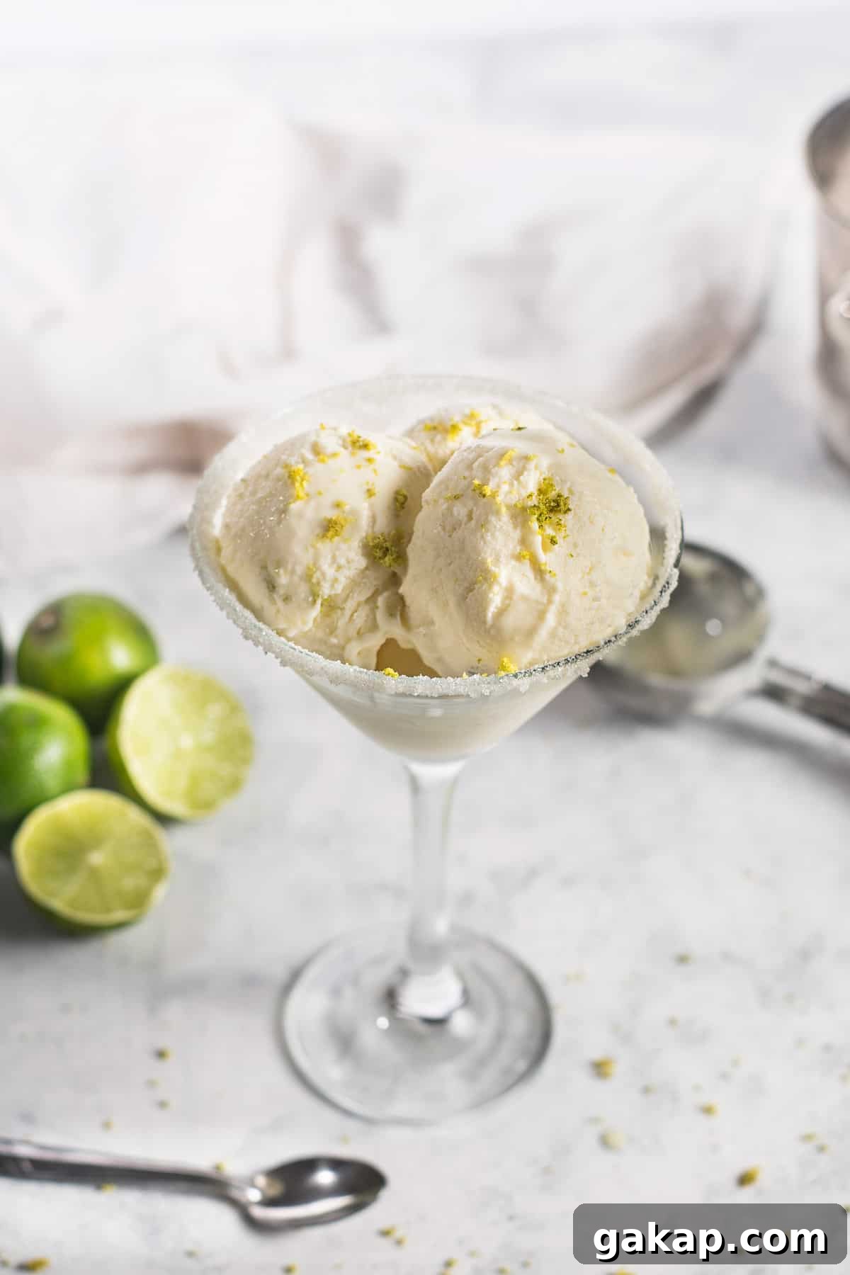 No-Churn Margarita Ice Cream: Creamy Lime & Tequila Recipe 12 A glass with scooped margarita ice cream and lime on a white background.