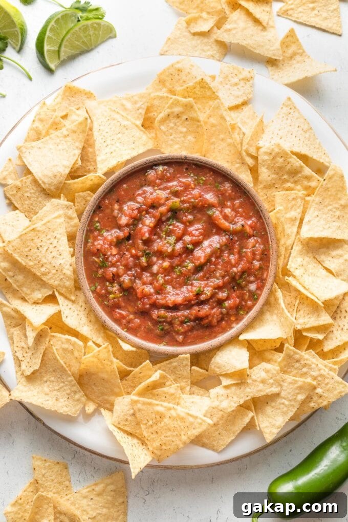 Bowl of blender salsa on a tray surrounded by tortilla chips.