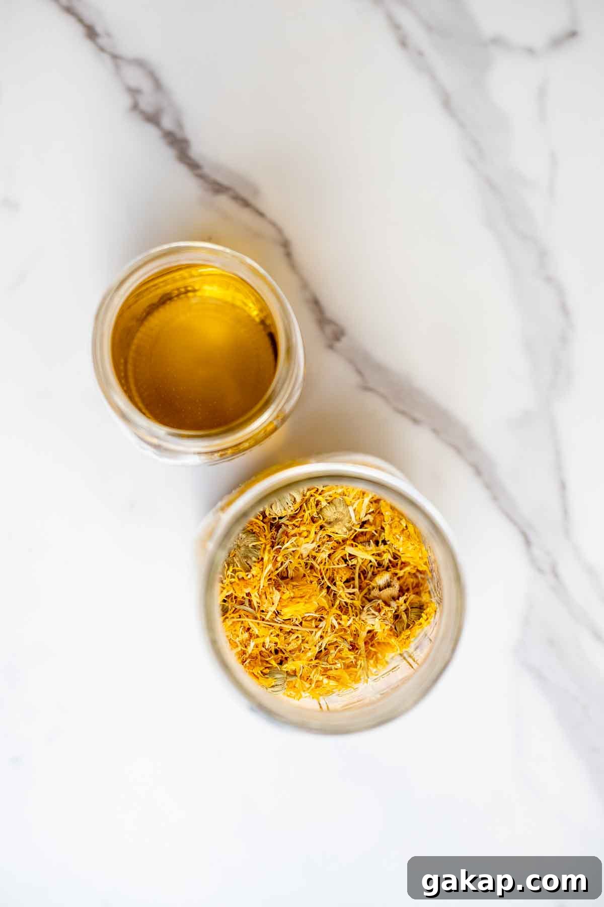 a jar of oil and a jar of dried flowers on a countertop.
