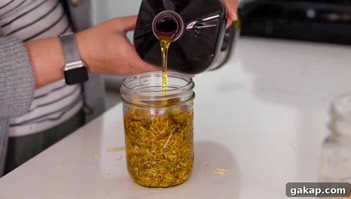 Pouring oil into a mason jar with calendula oil.