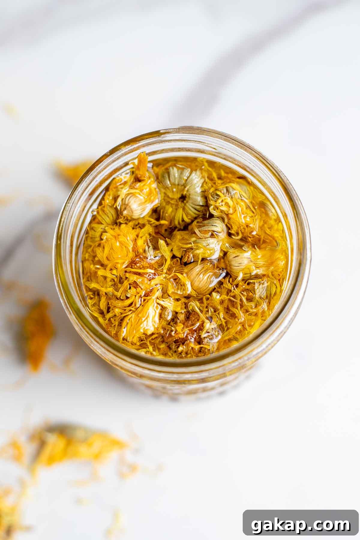 Overhead photo of a jar of calendula oil with dried calendula in it.