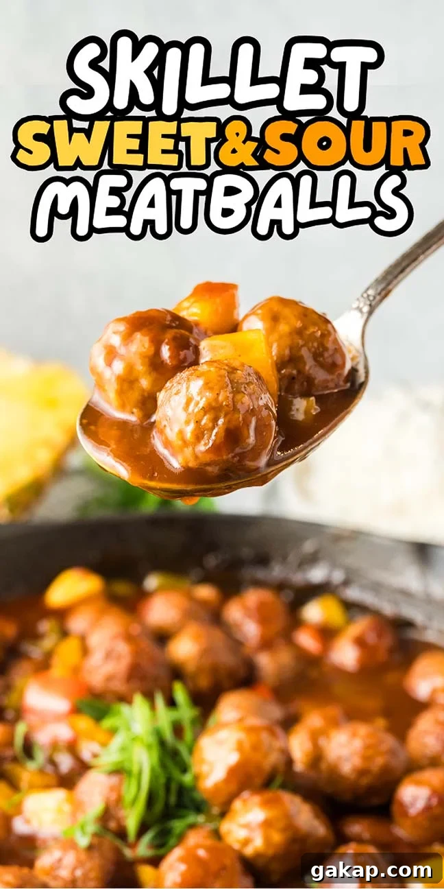 A spoonful of sweet and sour meatballs glistens over a skillet brimming with savory meatballs and vibrant vegetables.