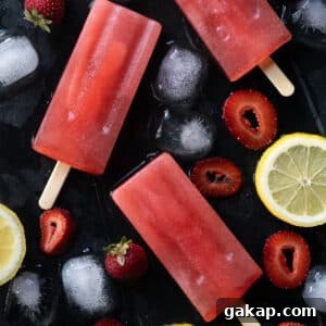 Keto strawberry lemonade popsicles on black marble with ice
