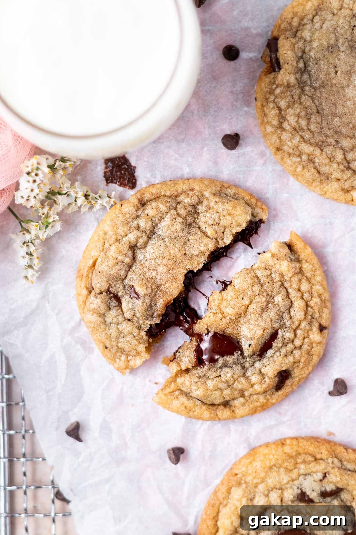 Crispy Thin Chocolate Chip Cookies: Crunchy, Perfectly Baked 10 broken cookie on a parchment lined cooling rack with a glass of milk