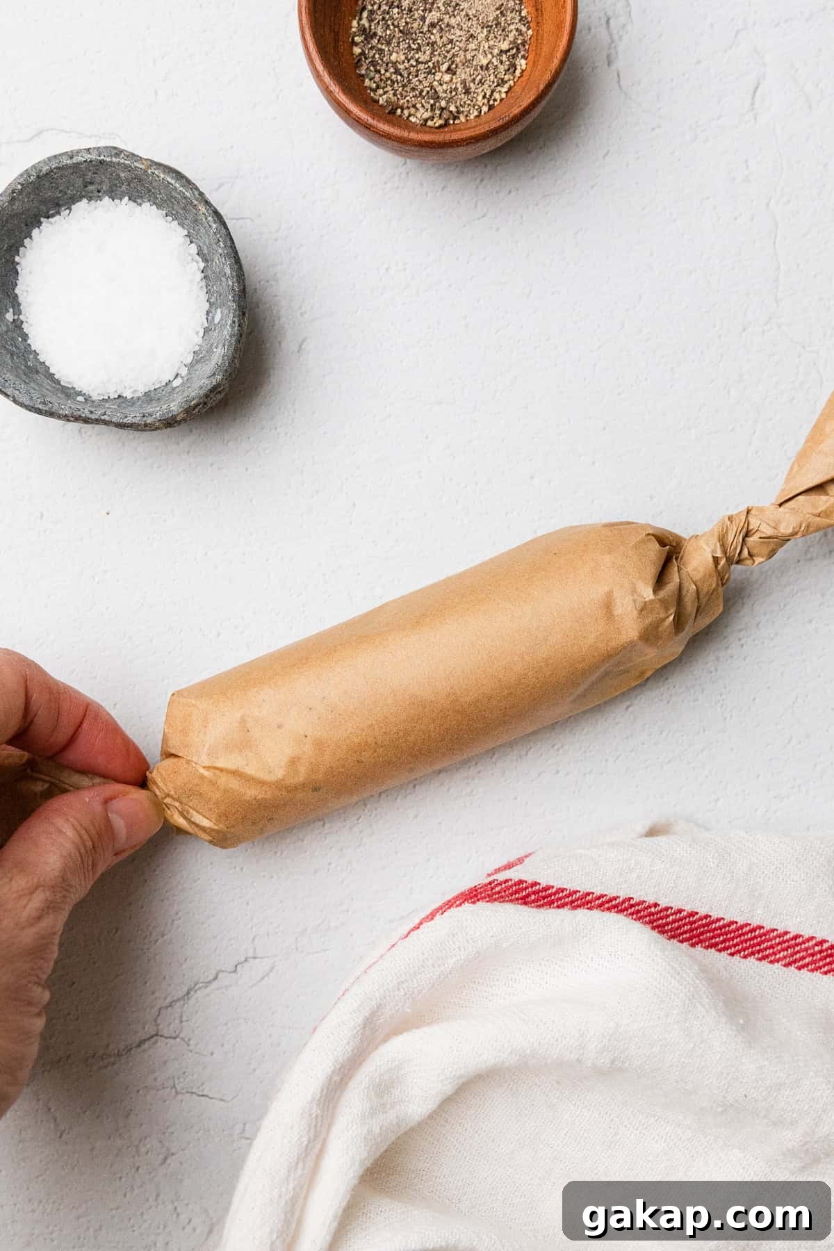 Rolling the butter into a log using the parchment paper.