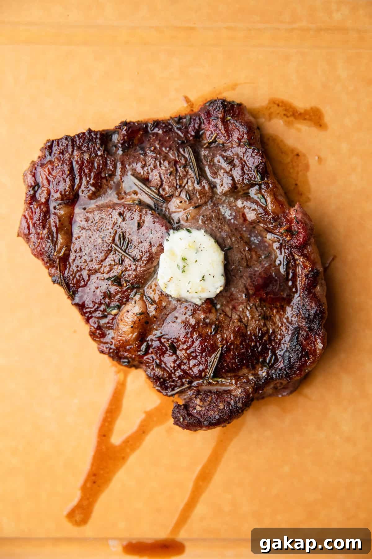 The herb and garlic butter placed on top of a cooked steak.