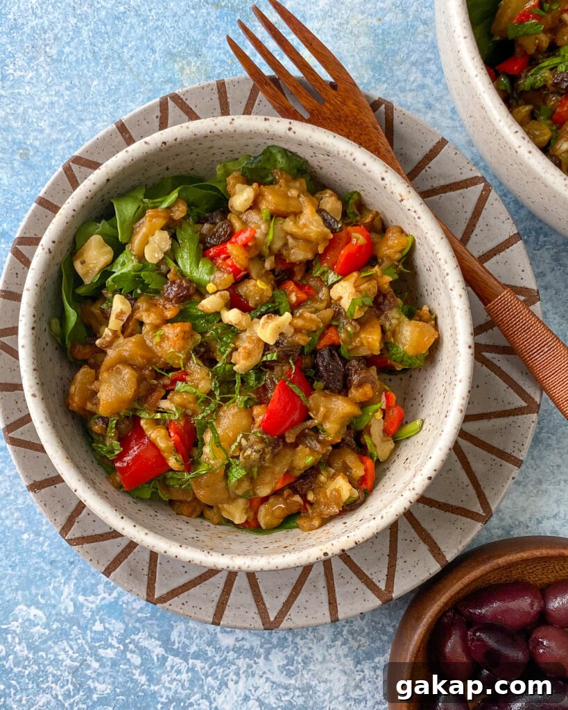 overhead view of a small bowl of eggplant salad with herbs, peppers and nuts