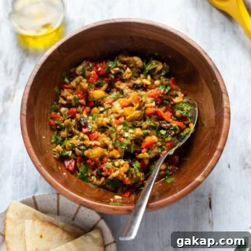 Overhead view of a bowl of eggplant salad, a side of pita bread and some extra virgin olive oil