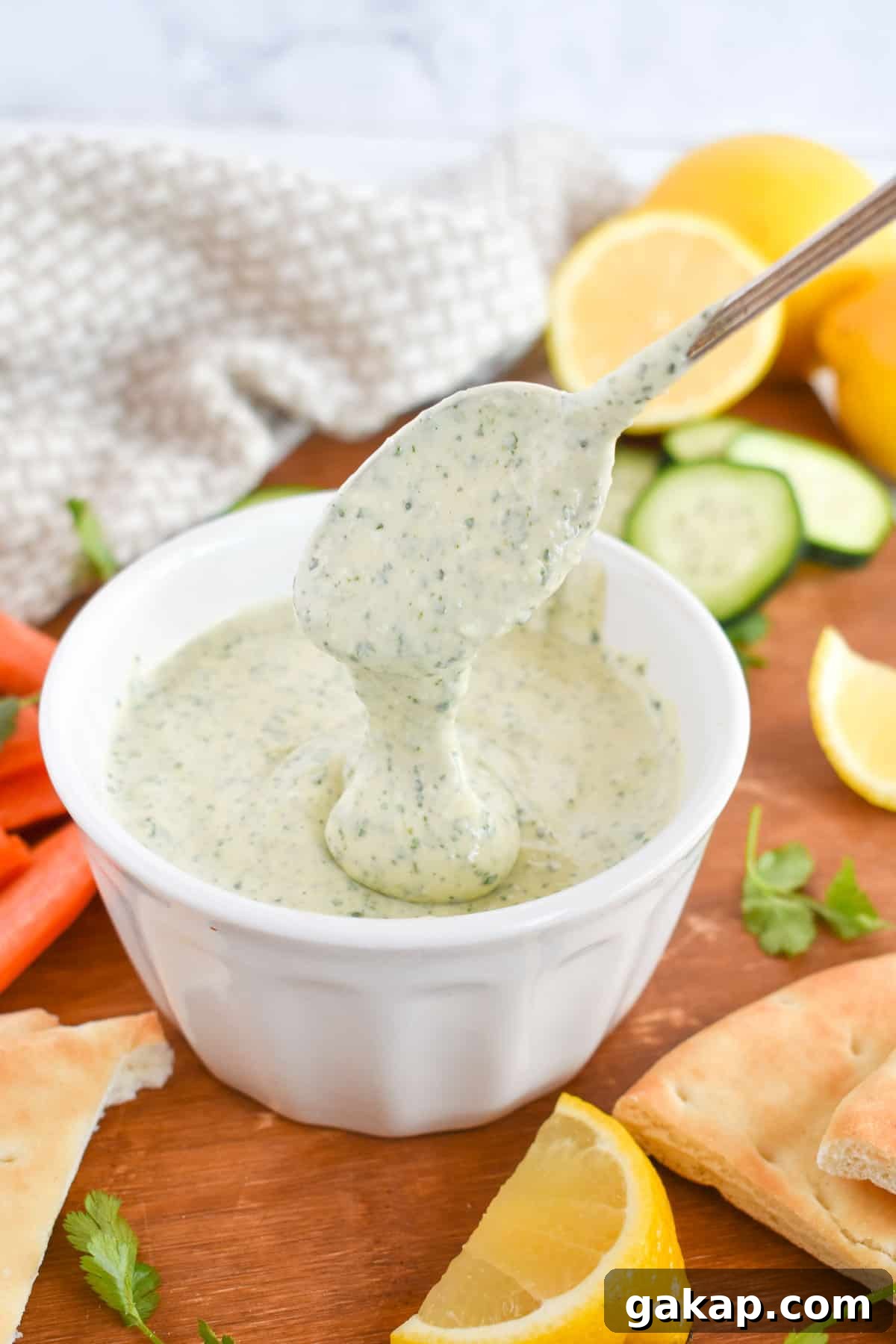 spoon drizzling tahini sauce into bowl. 
