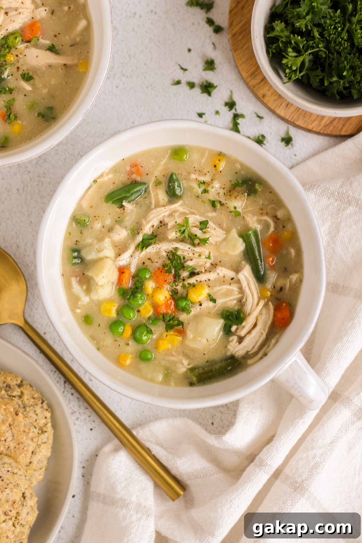 Dairy-Free, Gluten-Free Chicken Pot Pie Soup Recipe 11 Single serving bowl filled with chicken pot pie soup with a second bowl and a plate of biscuits off to the side.
