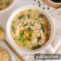 Dairy-Free, Gluten-Free Chicken Pot Pie Soup Recipe 16 Bowl of creamy chicken pot pie soup with a gold spoon on the side.