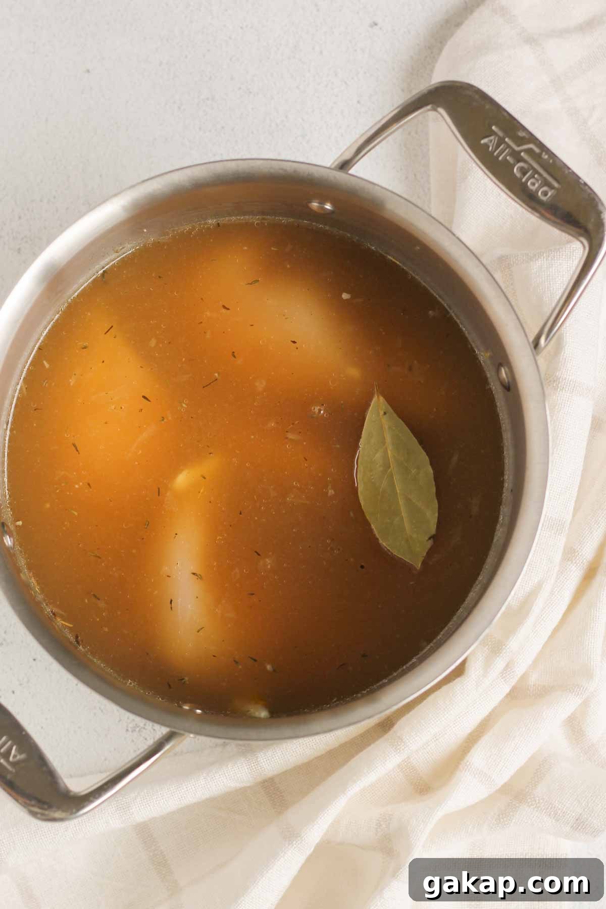 Dairy-Free, Gluten-Free Chicken Pot Pie Soup Recipe 5 Chicken breasts covered with broth and a bay leaf in a stainless steel stock pot.