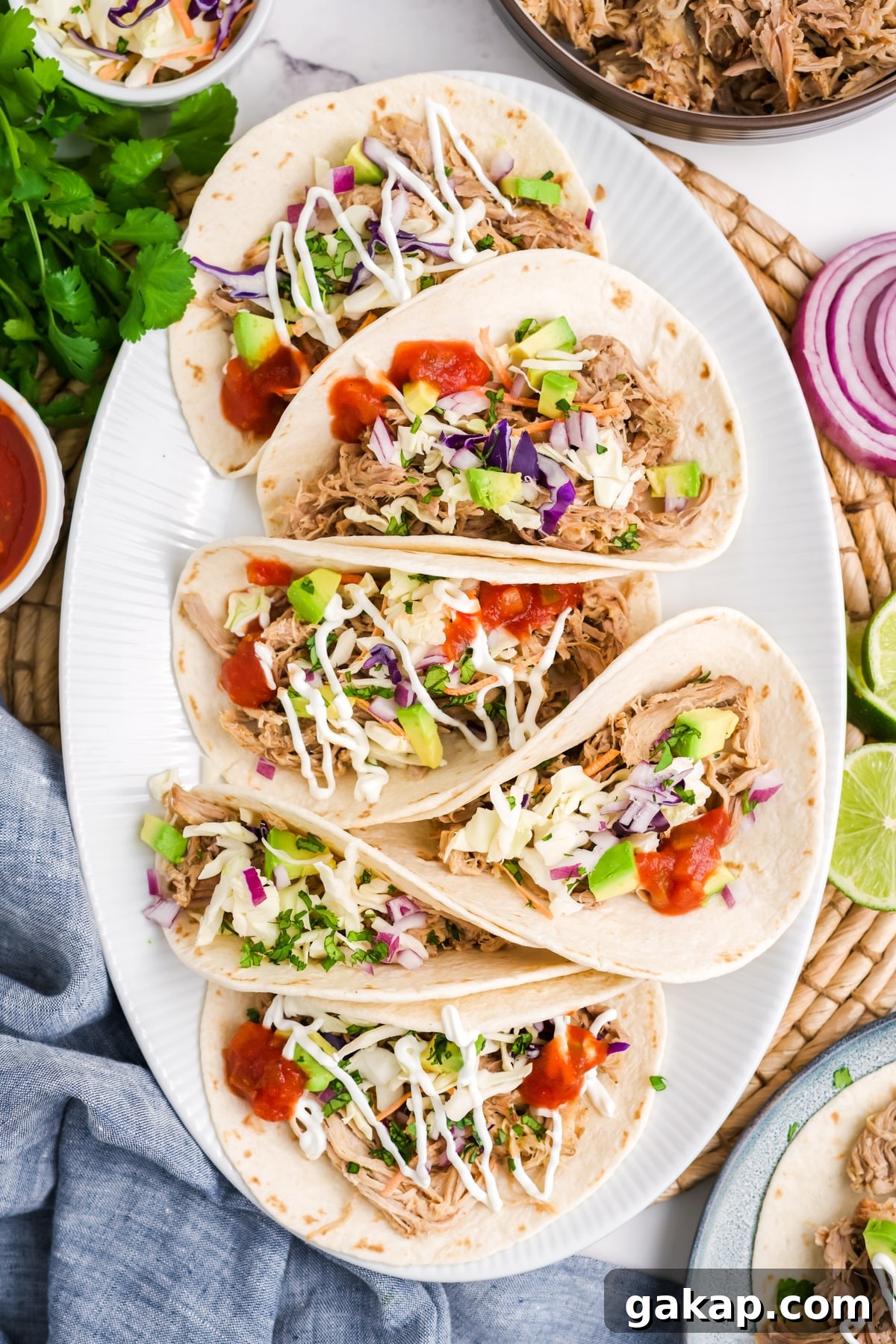 A plate filled with six pulled pork tacos with limes for garnish.