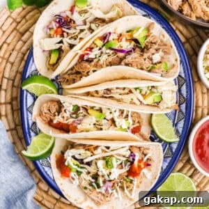 A plate with pulled pork tacos with lime garnish.