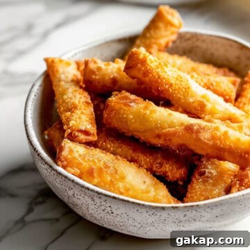 Crispy fried homemade egg rolls in a white bowl.