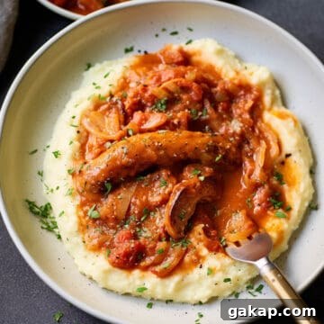 Slow cooker sausage casserole over mashed potatoes with mushrooms and peppers.
