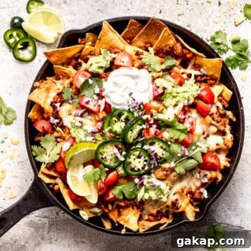 Loaded cheese nachos with chicken in a skillet.