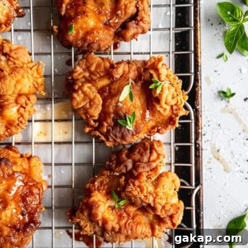 Crispy buttermilk chicken on a cooling rack with sea salt and thyme leaves.
