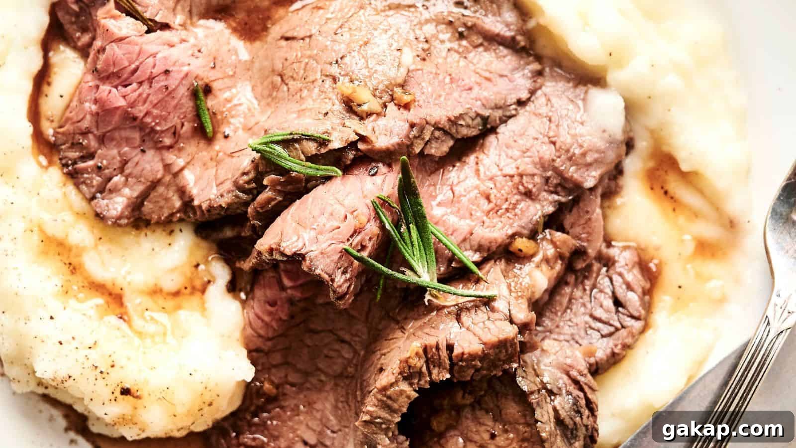Sliced roast beef served on a bed of mashed potatoes, garnished with fresh rosemary.