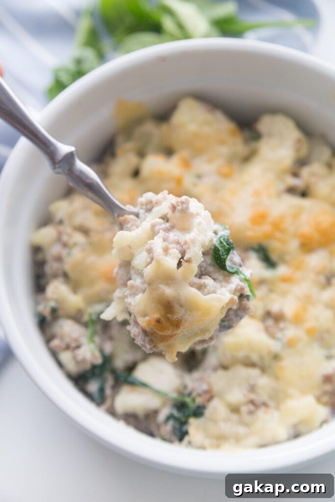 A white ceramic bowl with sausage and cauliflower casserole made with ricotta and Parmesan cheese