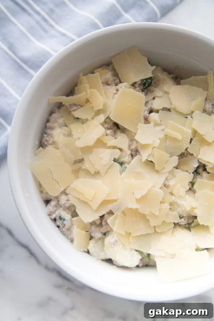A white ceramic bowl with sausage and cauliflower casserole made with ricotta and Parmesan cheese