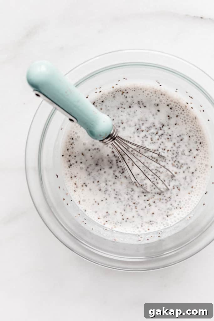 chia seeds and almond milk in a mixing bowl with a blue whisk