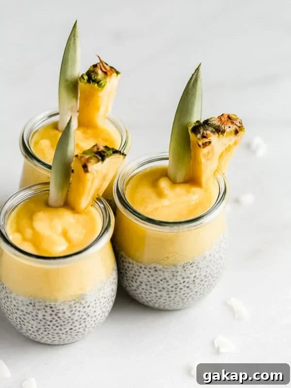 3 jars of pina colada chia pudding with pineapple wedges in them on a marble board