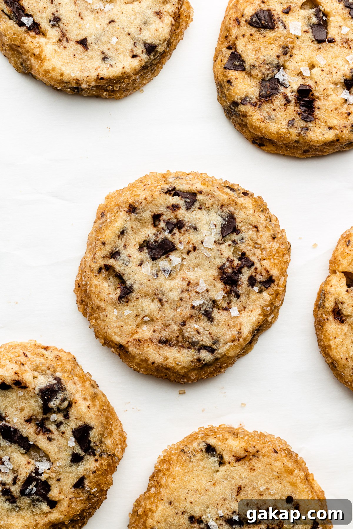 Brown Butter Miso Shortbread with Dark Chocolate Chunks 2 miso shortbread cookies with brown butter and chocolate chunks on parchment paper