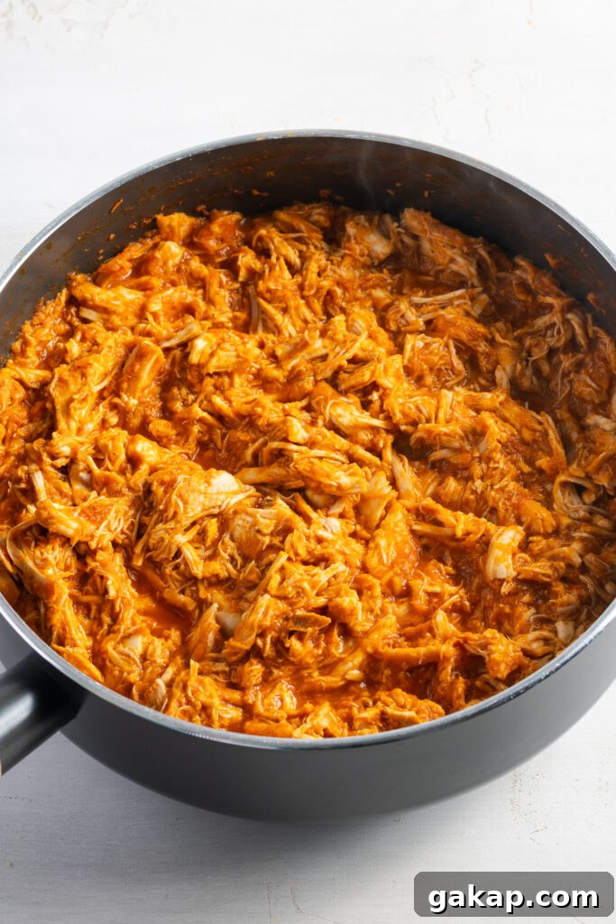 shredded cooked chicken tossed in the spicy tomato tinga sauce in a large skillet.