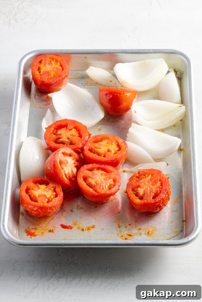 roasted tomatoes and white onions on a baking sheet.